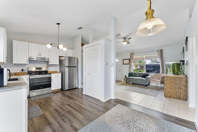 kitchen featuring appliances with stainless steel finishes, lofted ceiling, under cabinet range hood, light countertops, and dark wood finished floors