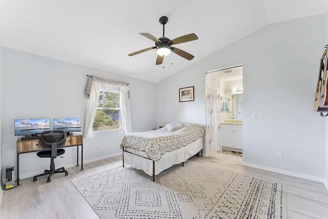bedroom with vaulted ceiling, light wood-style flooring, baseboards, ensuite bath, and ceiling fan