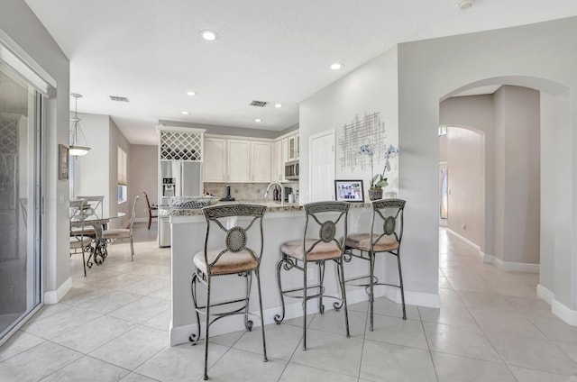 12774 Spikerush Cir, Boca Raton, FL 33428 - kitchen featuring a peninsula, a breakfast bar, stainless steel microwave, light stone countertops, and arched walkways