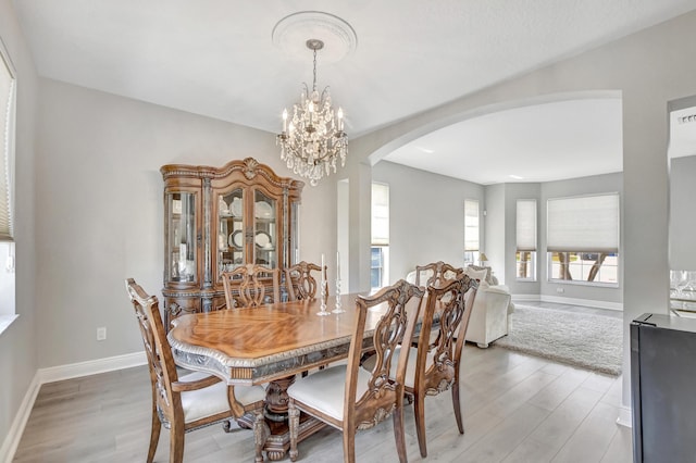 12774 Spikerush Cir, Boca Raton, FL 33428 - dining area with light wood-style flooring, baseboards, arched walkways, and a notable chandelier
