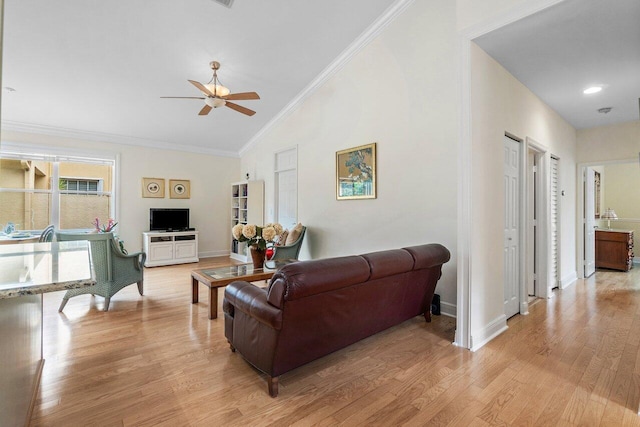 living area with a ceiling fan, baseboards, light wood-style floors, vaulted ceiling, and ornamental molding