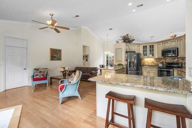 kitchen featuring a peninsula, cream cabinets, ornamental molding, visible vents, and appliances with stainless steel finishes
