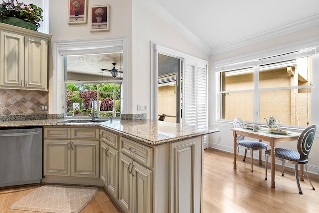 kitchen with light wood finished floors, cream cabinets, a sink, dishwasher, and vaulted ceiling