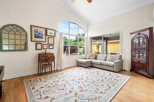living room featuring ornamental molding, light wood-type flooring, high vaulted ceiling, a ceiling fan, and baseboards