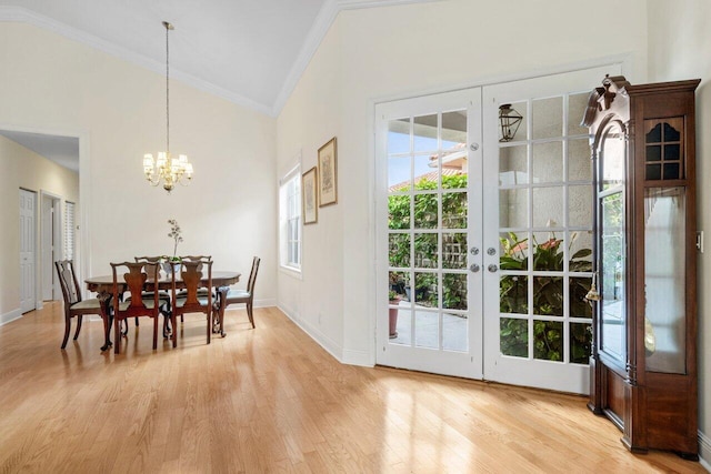 dining area with ornamental molding, light wood-type flooring, vaulted ceiling, a chandelier, and baseboards