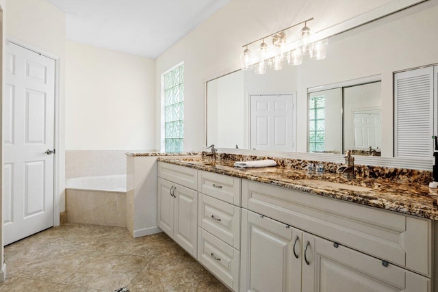 bathroom with a sink, double vanity, a bath, and plenty of natural light