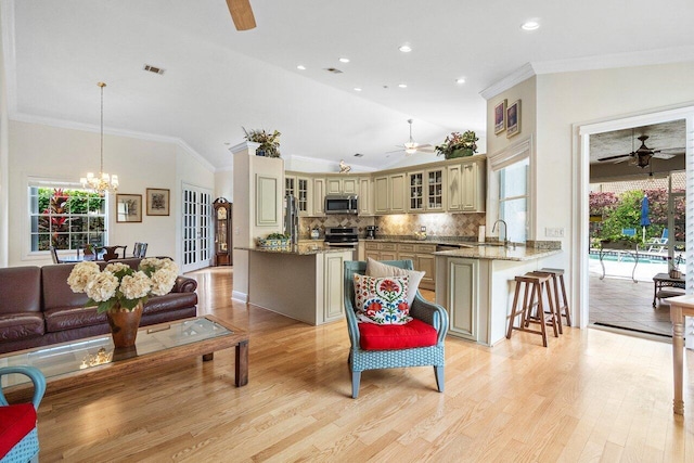 living area featuring light wood finished floors, ceiling fan with notable chandelier, visible vents, and recessed lighting