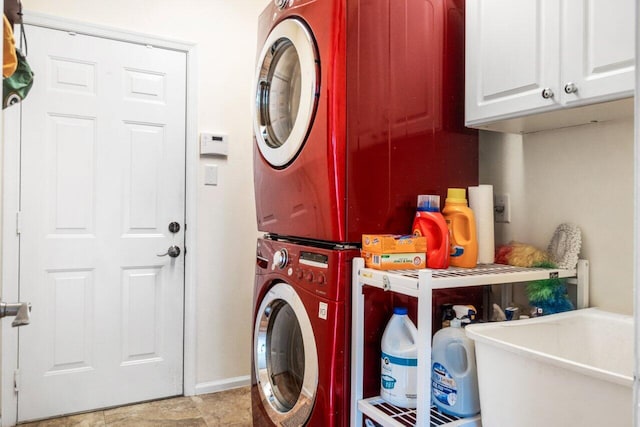 laundry area with cabinet space, baseboards, and stacked washer / drying machine