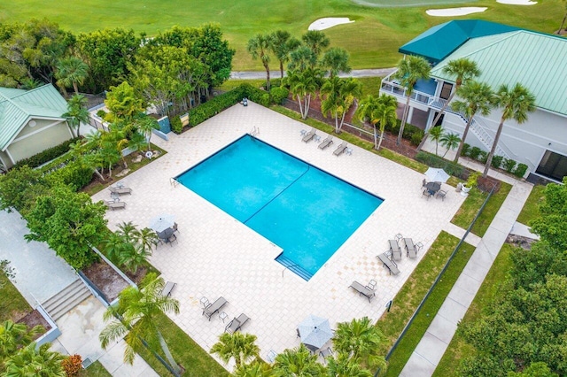 community pool with view of golf course and a patio