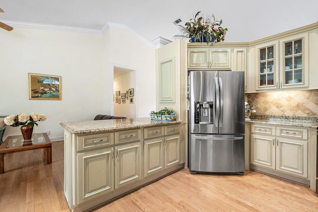 kitchen with light wood finished floors, a peninsula, crown molding, stainless steel refrigerator with ice dispenser, and cream cabinets