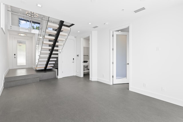 foyer featuring stairway, baseboards, and a chandelier