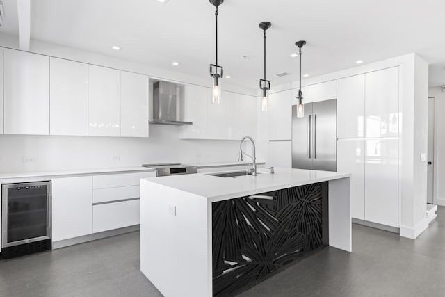 kitchen featuring wall chimney range hood, beverage cooler, modern cabinets, a sink, and appliances with stainless steel finishes