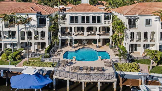 community pool with fence, a dock, and a patio area