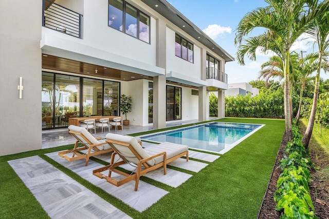 1445 NE 5th Ave, Boca Raton, FL 33432 - rear view of property with a balcony, stucco siding, a patio area, an outdoor pool, and a lawn