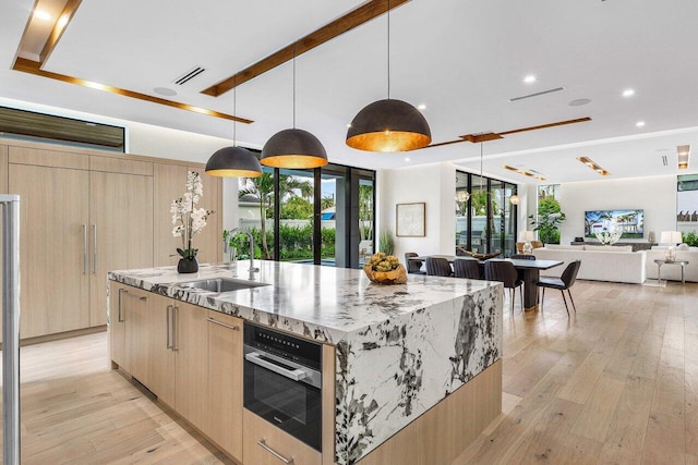 1445 NE 5th Ave, Boca Raton, FL 33432 - kitchen with modern cabinets, light brown cabinets, a sink, a large island with sink, and light wood-style floors