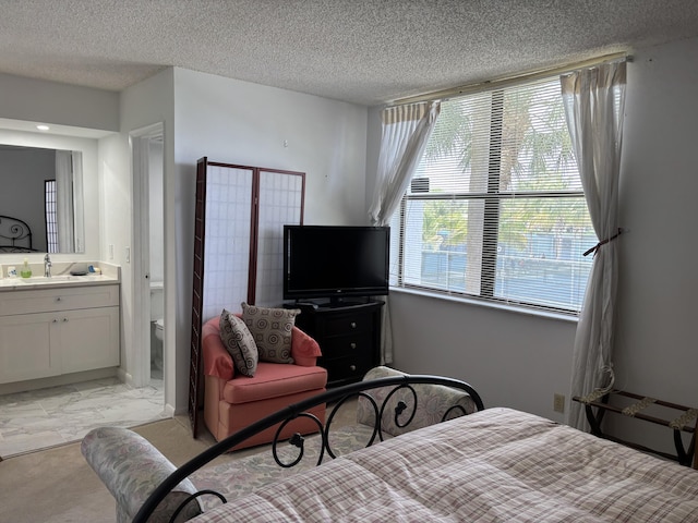 825 Egret Cir Unit 205, Delray Beach, FL 33444 - bedroom featuring a sink, light marble finish floors, a textured ceiling, and connected bathroom