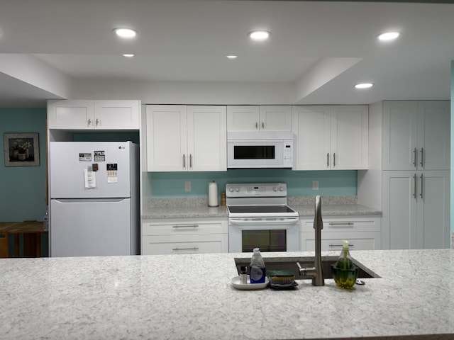 825 Egret Cir Unit 205, Delray Beach, FL 33444 - kitchen featuring white appliances, recessed lighting, white cabinets, and light stone counters