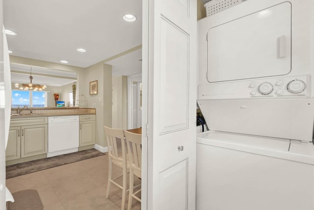 10200 S Ocean Dr Unit 303, Jensen Beach, FL 34957 - clothes washing area with a sink, laundry area, an inviting chandelier, light tile patterned floors, and stacked washing maching and dryer