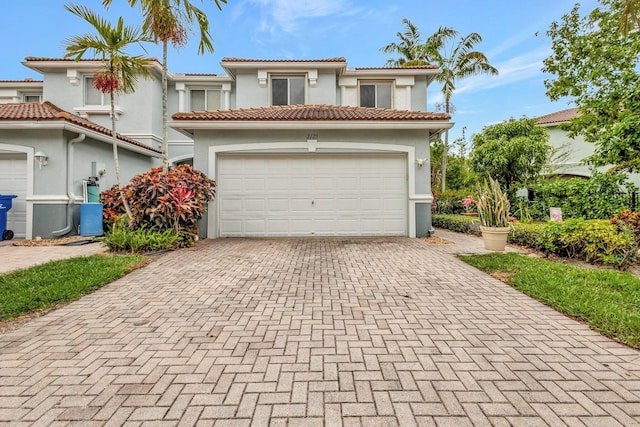 2125 Oakmont Dr, Riviera Beach, FL 33404 - mediterranean / spanish house featuring a tile roof, stucco siding, an attached garage, and decorative driveway
