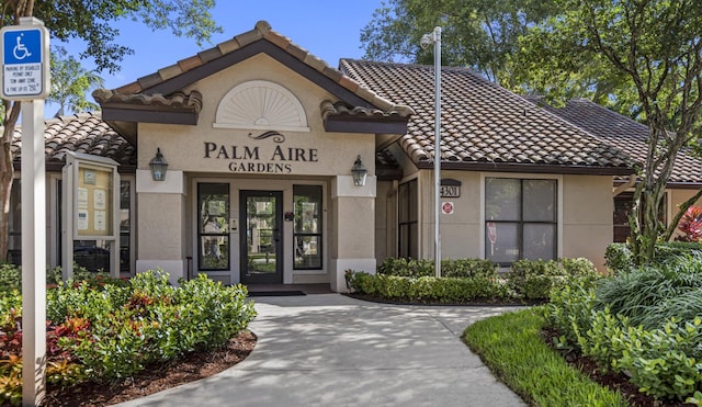 entrance to property featuring a tiled roof and stucco siding