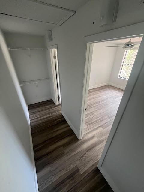 hall with wood finished floors, baseboards, and attic access