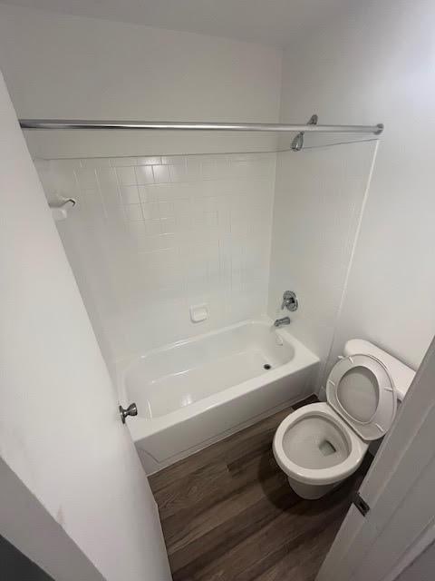bathroom featuring toilet, wood finished floors, and tub / shower combination
