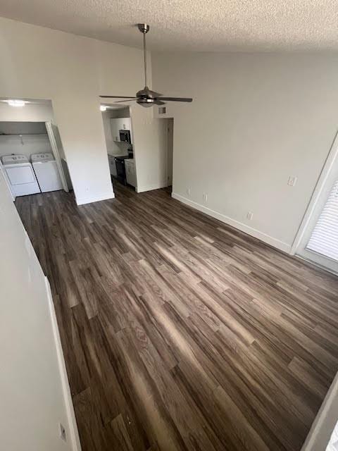 unfurnished dining area with separate washer and dryer, a textured ceiling, dark wood-style flooring, ceiling fan, and baseboards