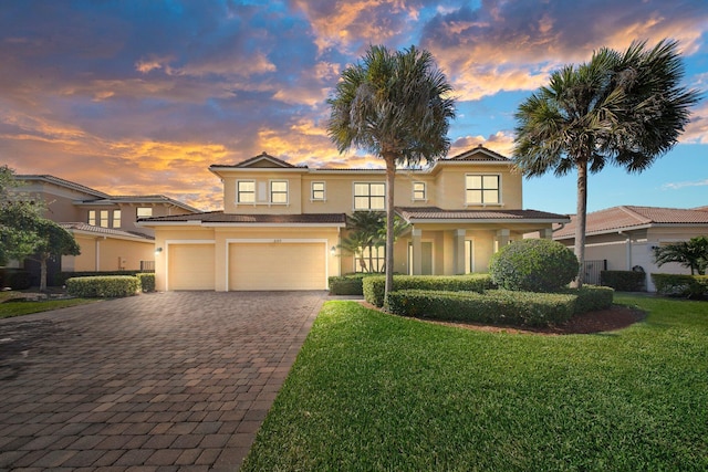 traditional-style home featuring a front yard, stucco siding, an attached garage, and decorative driveway
