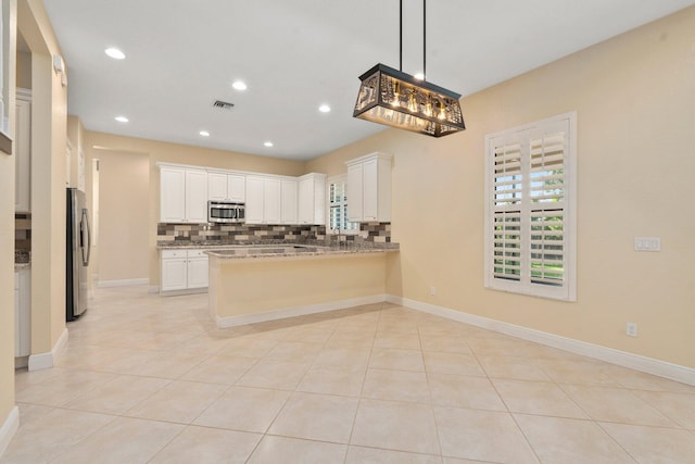 kitchen with light stone countertops, visible vents, a peninsula, tasteful backsplash, and appliances with stainless steel finishes