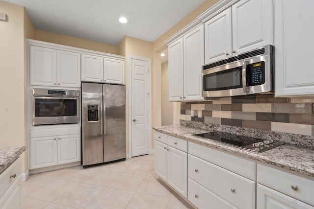 kitchen featuring stainless steel appliances, white cabinetry, light stone counters, and light tile patterned floors