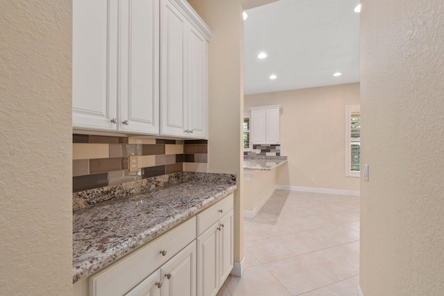 kitchen with tasteful backsplash, light stone counters, recessed lighting, a textured wall, and light tile patterned floors