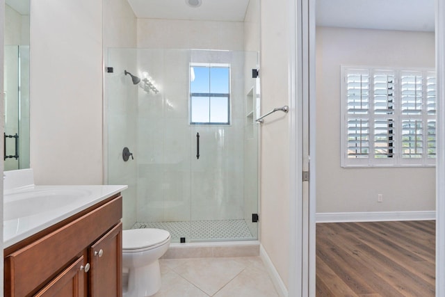 full bath with a stall shower, vanity, toilet, and baseboards