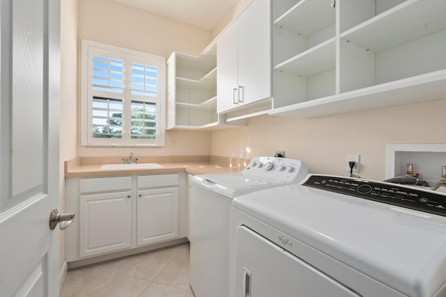 washroom featuring a sink, cabinet space, light tile patterned floors, and washer and dryer