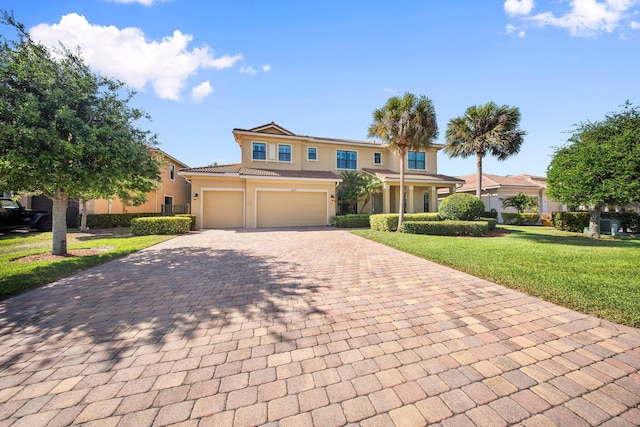 view of front facade with an attached garage, a tile roof, stucco siding, a front yard, and decorative driveway