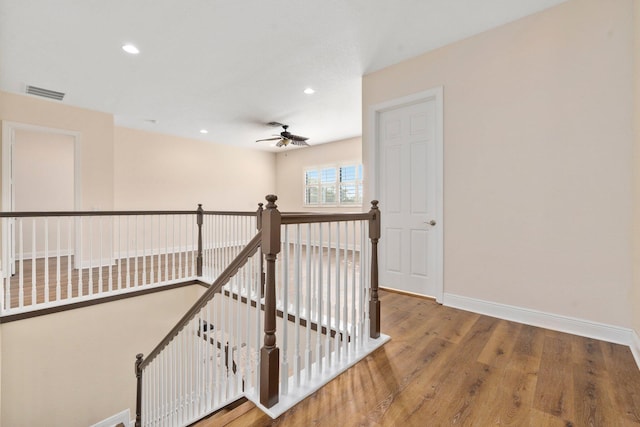 corridor featuring wood finished floors, an upstairs landing, visible vents, baseboards, and recessed lighting