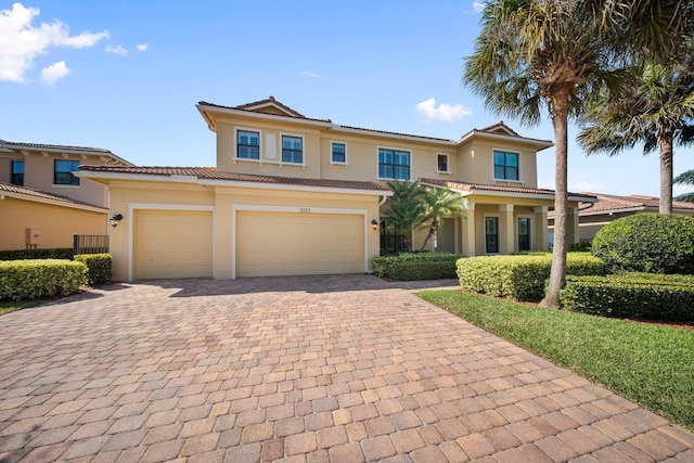 view of front facade with a tiled roof, stucco siding, decorative driveway, and a garage