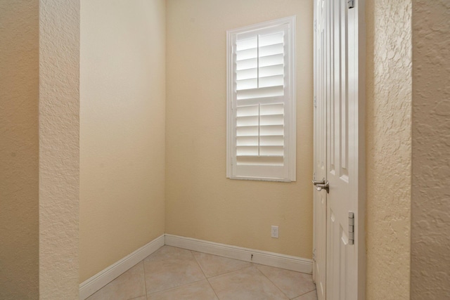 spare room featuring tile patterned flooring, baseboards, and a textured wall
