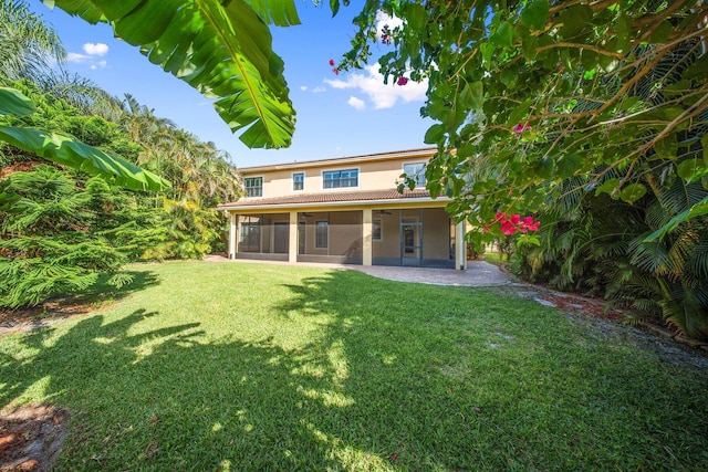 rear view of house featuring a yard, stucco siding, a sunroom, and a patio
