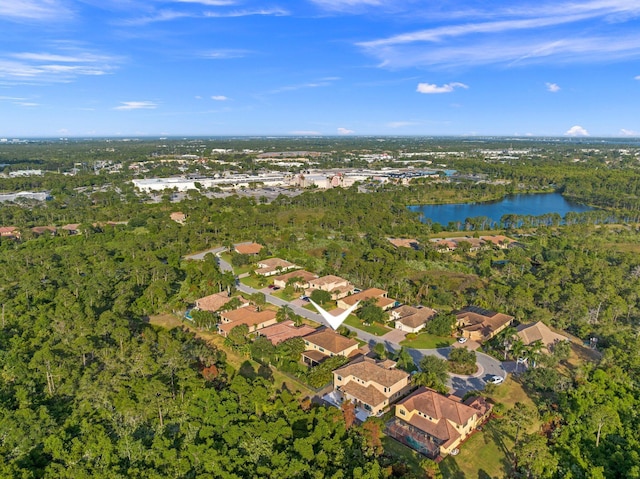 drone / aerial view featuring a wooded view, a water view, and a residential view