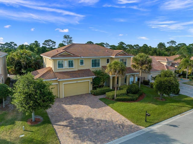 view of front of property with decorative driveway, a garage, stucco siding, a tile roof, and a front lawn