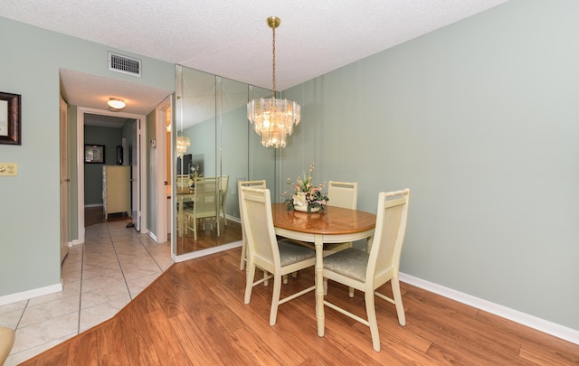 dining room featuring light wood finished floors, a notable chandelier, baseboards, and visible vents