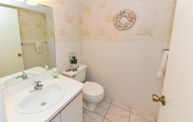 bathroom with tile walls, wallpapered walls, toilet, wainscoting, and vanity