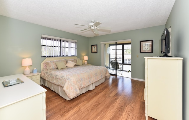 bedroom featuring baseboards, ceiling fan, light wood-type flooring, and a textured ceiling
