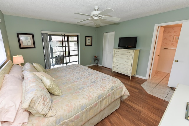 bedroom with a closet, wood finished floors, a textured ceiling, a ceiling fan, and baseboards