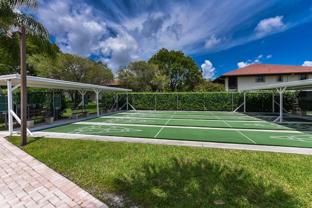 view of home's community featuring shuffleboard, fence, and a lawn