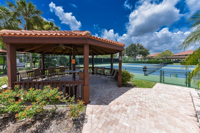 view of property's community with a gazebo, a tennis court, fence, and a gate