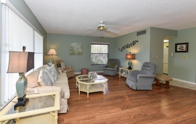 living area with wood finished floors, a textured ceiling, visible vents, ceiling fan, and baseboards