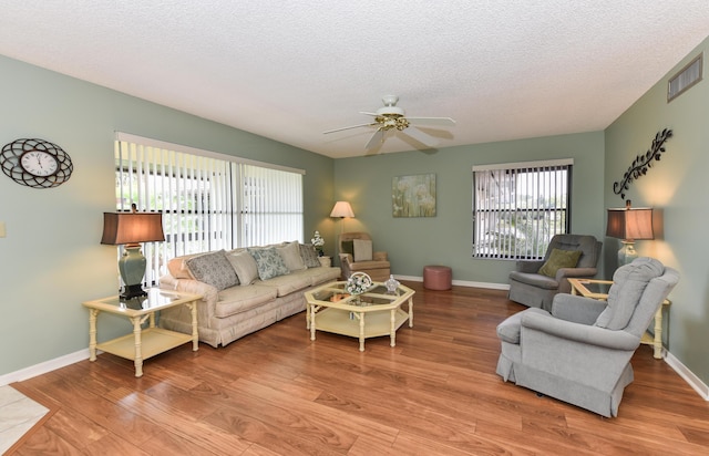 living area featuring plenty of natural light, a ceiling fan, visible vents, and wood finished floors