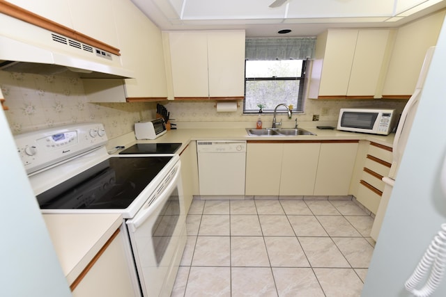 kitchen with a sink, white appliances, under cabinet range hood, and light countertops