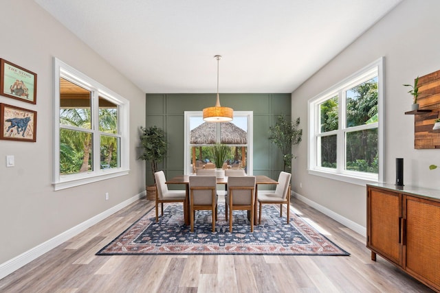 dining area with baseboards, light wood finished floors, and a healthy amount of sunlight